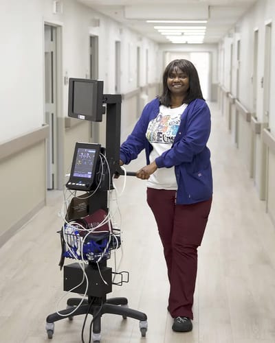 Staff member assisting with medical equipment in a hallway