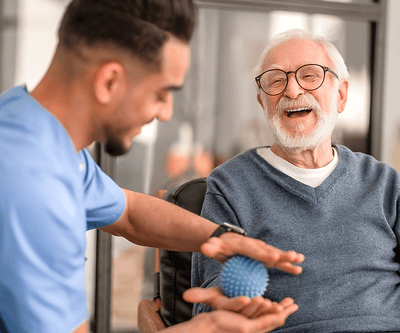 Elderly man laughing with caregiver and a ball