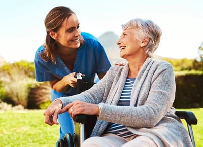 Healthcare worker smiling with a resident outdoors