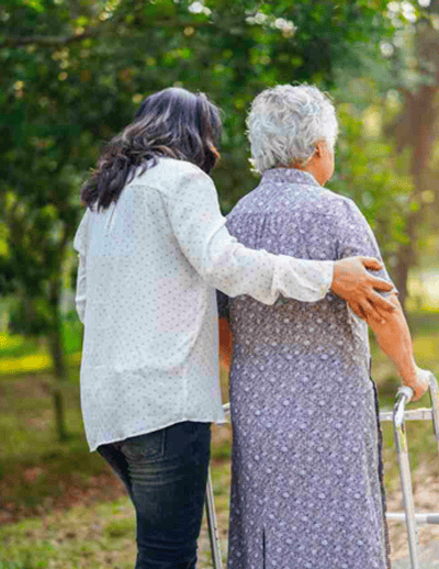Caregiver assisting elderly woman with walker