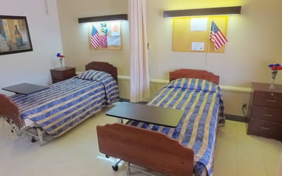 Two hospital beds in a shared room with decorations.