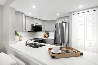 Modern kitchen with white cabinets and stainless steel appliances.