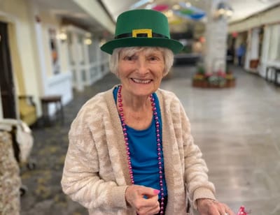 Smiling resident wearing a festive hat in a common area.