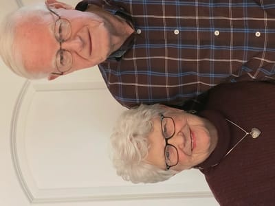 Elderly couple smiling together indoors.