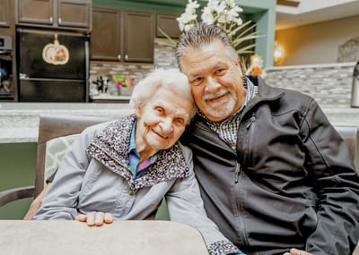 Elderly resident with staff member, smiling together.