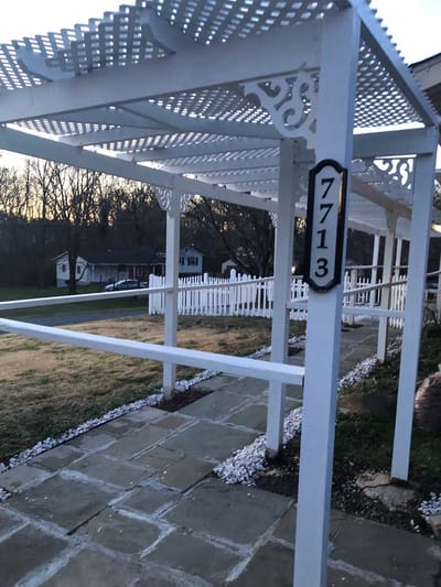 Outdoor structure with white lattice and house number.