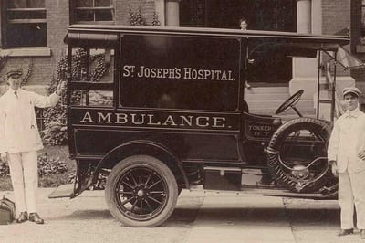 Historic ambulance with hospital branding outside a building