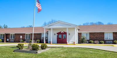 Exterior view of New Castle Health & Rehabilitation Center with flag