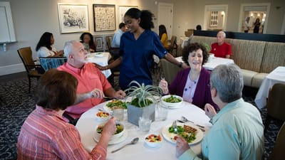 Residents enjoying a meal in the dining room with staff