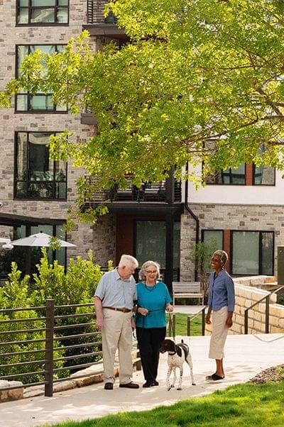 Residents walking outside with a dog near the facility