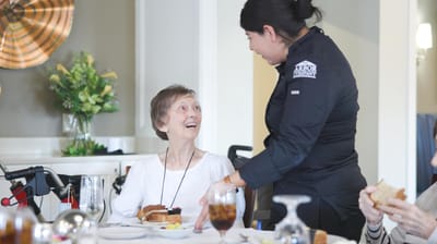 Staff serving meals to residents in a dining room