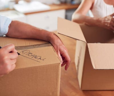 Two hands packing boxes in a kitchen