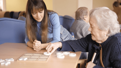 Staff member and resident playing a game indoors