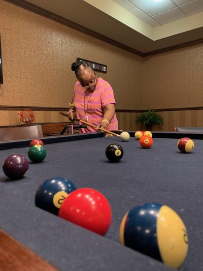 Resident playing pool in an activity room