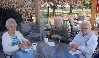 Three residents enjoying snacks and coffee outside