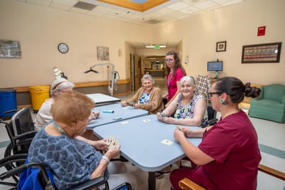 Residents and staff engaged in a card game in a common area