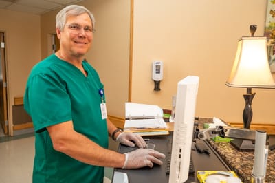 A staff member with a computer in an office setting
