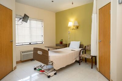 Private resident room with a hospital bed and chair