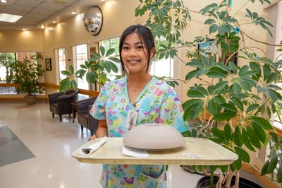 Staff member carrying a meal tray in a bright interior