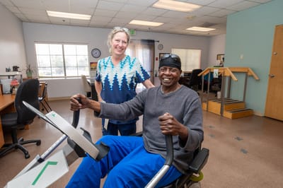 A staff member assisting a resident in a therapy exercise area