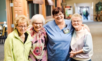 Staff member posing with residents in a common area