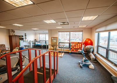 Rehabilitation room with therapy equipment and large windows