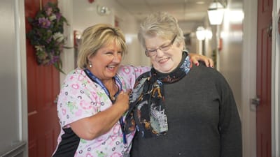 Care staff and resident smiling in the hallway