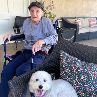 Resident in a wheelchair with a dog outdoors