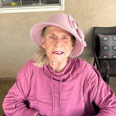 A smiling resident wearing a pink hat outdoors