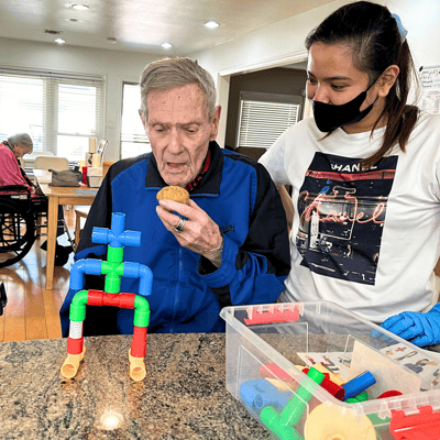 Resident enjoying a cookie with staff assistance
