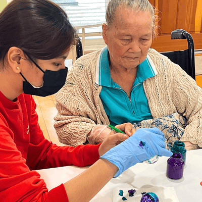 A staff member assists a resident in a craft activity.