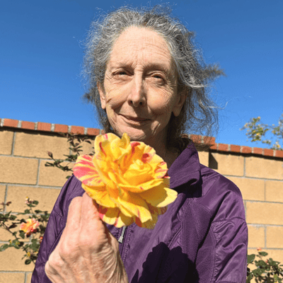 Resident holding a flower in a garden