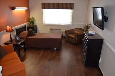 Brightly lit private resident room with furnishings