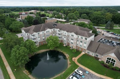 Aerial view of a nursing facility with a pond and surrounding green space