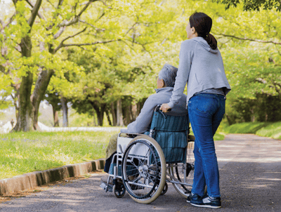 Resident in wheelchair enjoying a sunny outdoor path