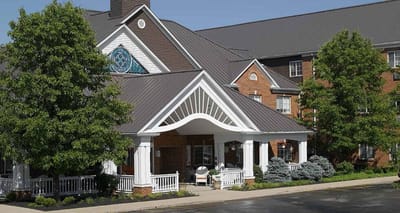 Front entrance of a senior living facility with greenery