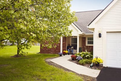 A resident sitting outside a cozy facility entrance