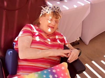 Resident wearing a crown, smiling in a colorful outfit