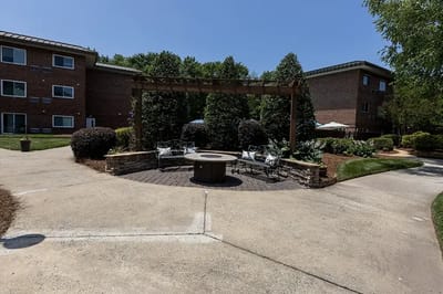 Outdoor seating area with a fire pit surrounded by greenery