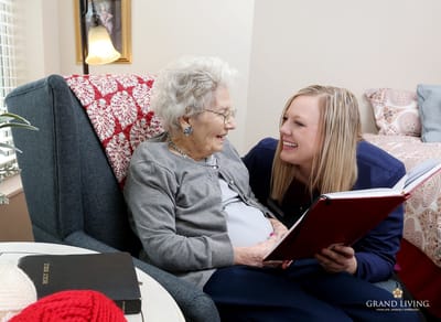 Staff member reading with a smiling resident