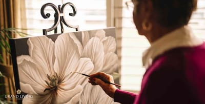 A resident painting a flower in an activity room