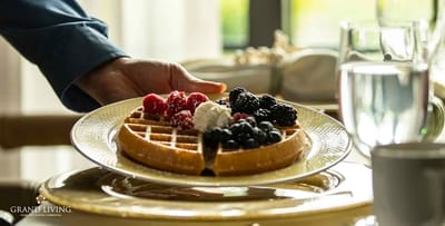 A hand serving a waffle topped with berries