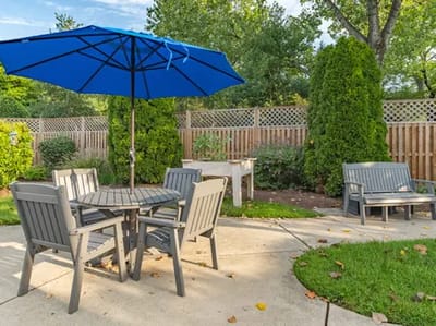 Outdoor seating area with a blue umbrella and greenery