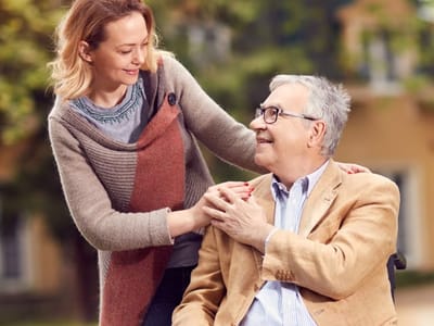 A caregiver assisting a senior man outdoors