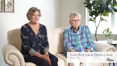 Two residents sitting together on a couch in a bright room