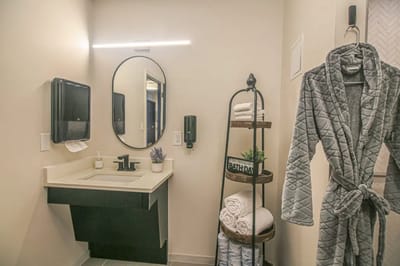 A well-lit and modern bathroom with a robe and towels