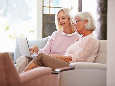 A caregiver and a senior resident using a laptop together