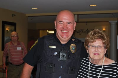 A smiling police officer with a resident in a facility lobby