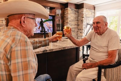 Two residents toasting drinks in a common area