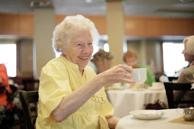 Elderly woman enjoying a drink in the dining area